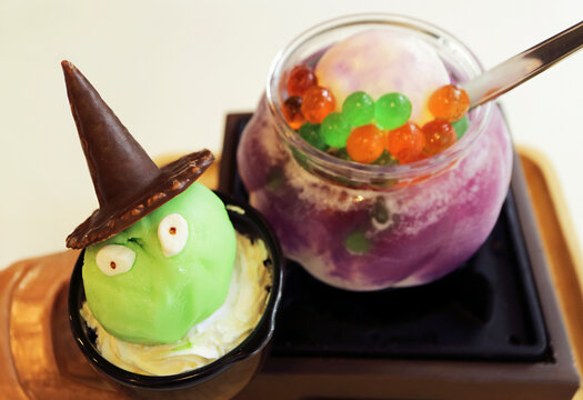 Cute Halloween green witch ice cream with blurred spooky cauldron cocktail background