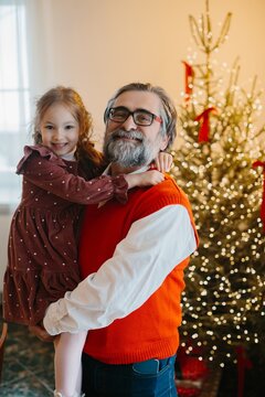 Grandfather holding smiling granddaughter celebrating christmas holidays