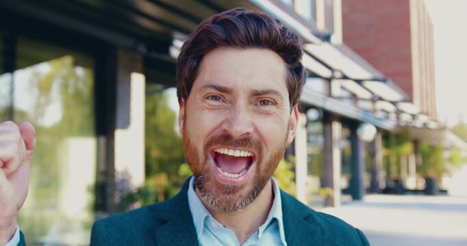 Portrait of a happy man looking at the camera, smiling and celebrating success with joyful hand gestures, expressing excitement, confidence, achievement, and positive emotions