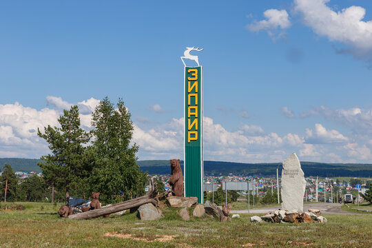 Bashkortostan, Russia - June 25, 2026: Roadside entrance stele of Zilair village in Bashkortostan Russia with bear sculptures and deer figure on hill overlooking houses