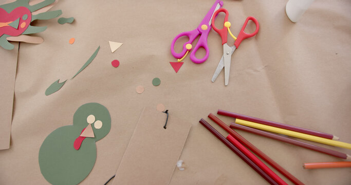 Coloured paper, crayons, scissors and cutouts lying on table