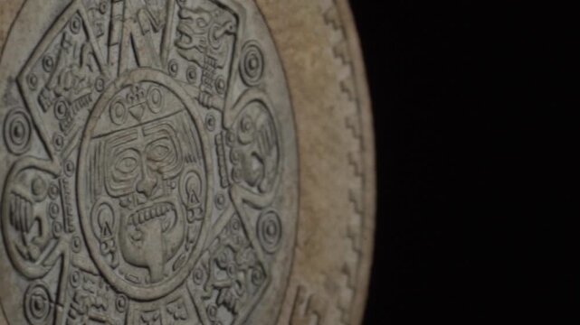 Closeup of Mexican 10 pesos bimetallic coin featuring Aztec Sun Stone design, intricate circular engravings, ancient symbols and central face motif on metallic surface.