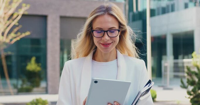 Portrait of businesswoman looking at the camera while using a tablet outdoors in an urban environment.