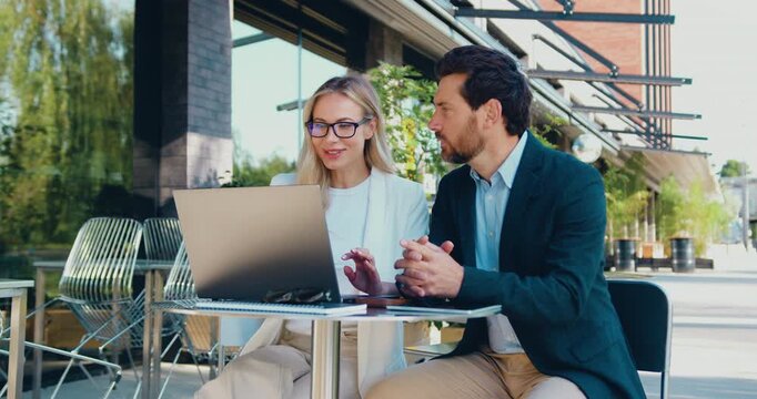 Businesswoman working on laptop with male colleague outdoors near office