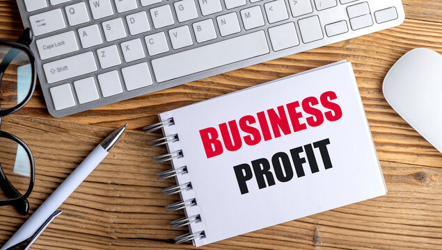 Business profit concept with notebook, keyboard and pen on wooden desk, illustrating entrepreneurship, revenue