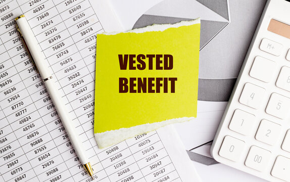 Vested benefit text on yellow paper with calculator, pen and financial reports, pension finance and retirement planning concept