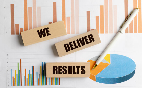 We deliver results text on wooden blocks with charts and pen, business performance and achievement concept