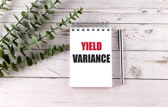 Yield variance text on a notebook with pen and green leaves on a wooden desk, production efficiency and accounting concept