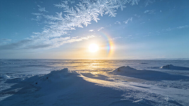 Mesmerizing arctic sun dog rainbow phenomenon glowing over icy snowdrifts with frost crystal patterns in a polar winter sky.