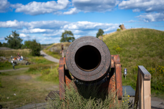 Weathered historic cannon dominates a grassy fortification landscape in Helsinki, Finland