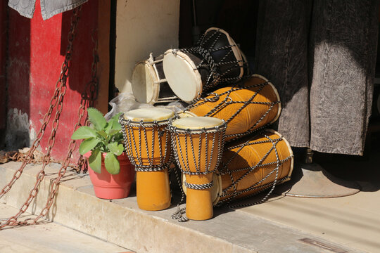 Traditional Indian dholak and djembe drums displayed at a music shop street market.