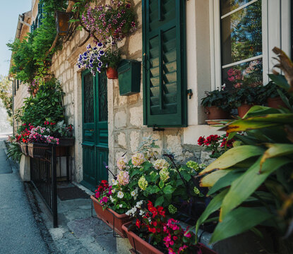 Beautiful Mediterranean stone house facade decorated with assorted flower pots and blooming plants.