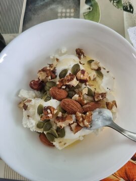 Bowl of yogurt topped with nuts and seeds on a dining table  