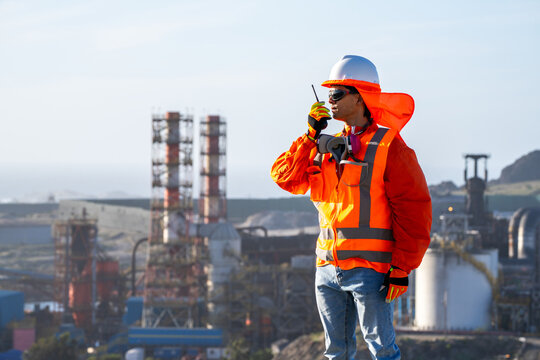 Industrial worker wearing protective gear and communicating by radio at an energy facility