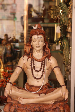 A colorful statue of Lord Shiva meditating in a lotus posture at a souvenir shop.