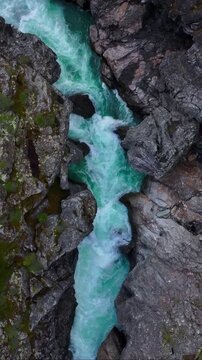 Turquoise glacial river flowing through a deep rocky mountain gorge a vertical