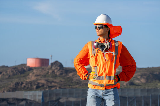 Industrial worker wearing a respirator and high-visibility gear, standing at a worksite