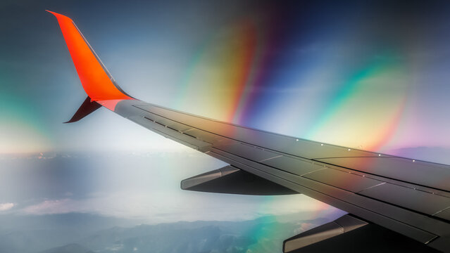wing of a civilian airliner airplane in flight with mountains with optical effect
