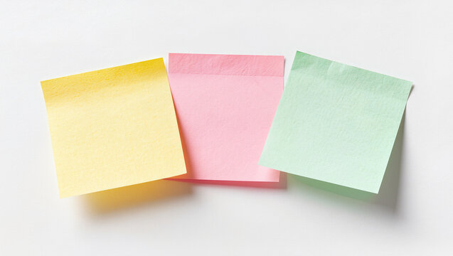 three blank sticky notes in yellow, pink and mint green overlapping on white with soft shadows, minimal studio photo, conceptual planning, reminders and organized ideas for office teamwork concept