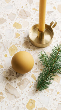 Terrazzo surface with mustard ornament, brass candleholder and fir sprig for Christmas flat lay