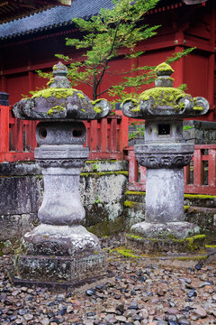 Stone lanterns with moss near red shrine fence at toshogu shrine