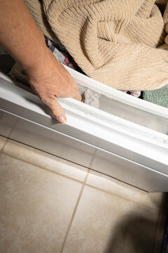 Hand gathering up contents of a dirty, dryer lint screen, filter, trap after drying a load of towels