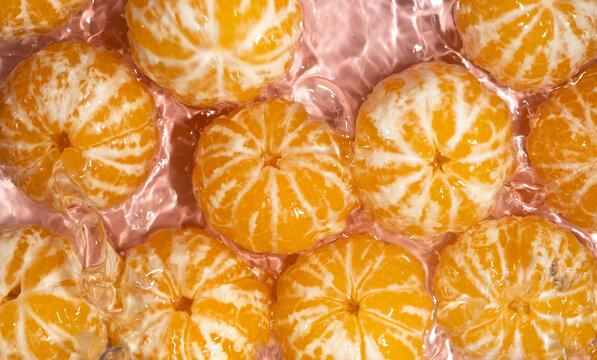 Peeled mandarins in water splash, fruity citrus background.