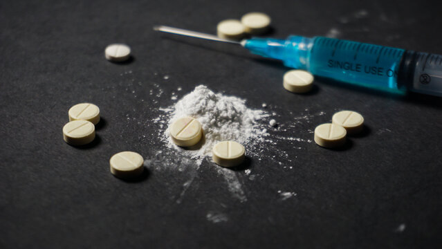 pills, white powder and one disposable medical syringe. Medication, misused drugs concept. 