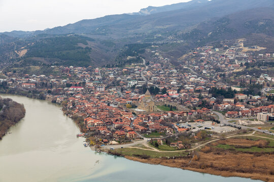 Old town with a medieval cathedral on the bank of a wide river below hills, Mtskheta-Mtianeti, Mtskheta, Georgia