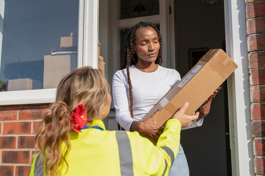 Delivery worker hands a parcel to a resident at her doorway