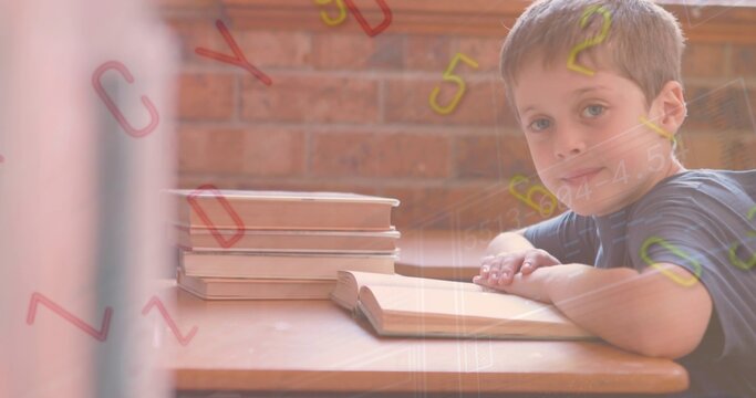 Sitting student wearing striped tee leaning on school desk with open book, stacked books