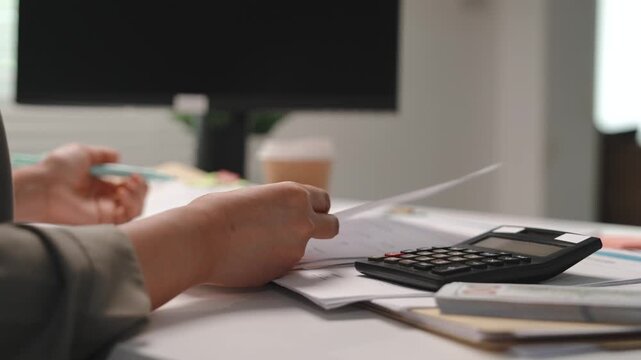 Accounting and finance, female accountant reviewing documents, writing notes with calculator at office desk, tax preparation, balance sheet, financial reporting and year end bookkeeping work.