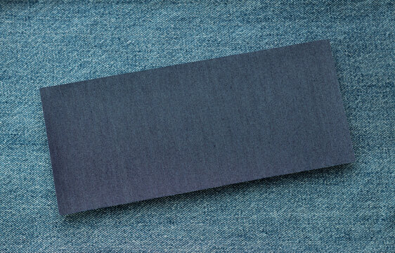 Blank dark denim fabric rectangle on blue jeans textile background. Clothing and apparel material sample for clothing and fashion design with copy space for branding, text