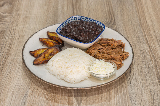 Venezuelan pabellon criollo dish with shredded beef, white rice, fried plantains, black beans, and shredded white cheese.