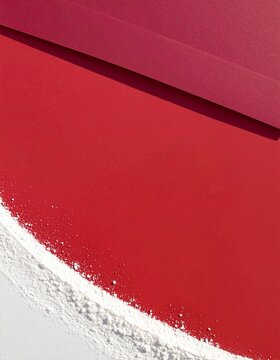Curved edge of fine white powder meeting a bright red surface, minimal overhead flat lay with copy space