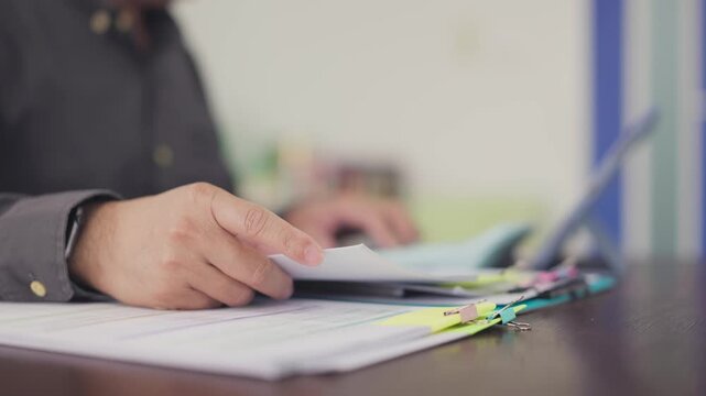 Businessman reviews paper documents, invoices contracts on desk in office. Corporate accounting audit, financial paperwork review, tax preparation workflow, legal contract management.
