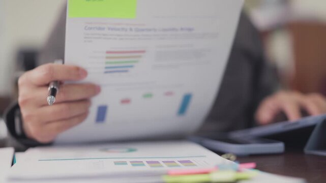 Auditor analyzes financial document charts holding pen in office. Corporate accounting audit review, quarterly liquidity assessment, investment risk analysis, business performance report.