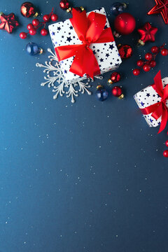 Blue Christmas and Happy New Year holiday background with gift boxes, red ribbon bows and festive red ornaments, flat lay with copy space. Greeting card.