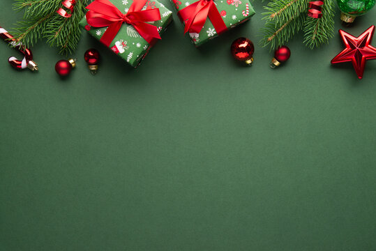 Merry Christmas and Happy Holidays greeting card, frame, banner. New Year. Red Christmas ornaments and gifts, presents on green background top view. Xmas holiday festive theme. Christmas decoration