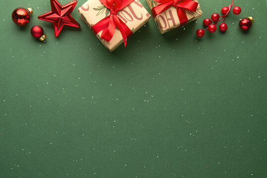 Merry Christmas and Happy Holidays greeting card, frame, banner. New Year. Red Christmas ornaments and gifts, presents on green background top view. Xmas holiday festive theme. Christmas decoration