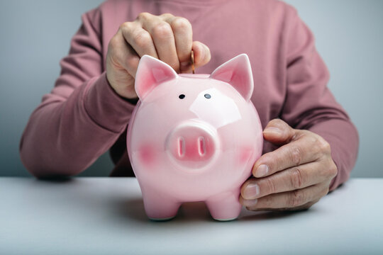 Piggy bank savings placing a coin into a piggybank, personal savings and financial planning