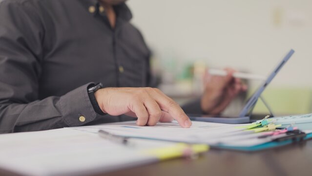 Auditor analyzes financial report paperwork beside digital tablet at workplace. Financial audit review, budget accounting management, corporate revenue analysis, tax calculation planning.