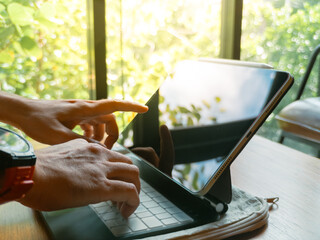 Person's hands typing on a tablet keyboard and touching the screen in a bright setting. © Sevendeman
