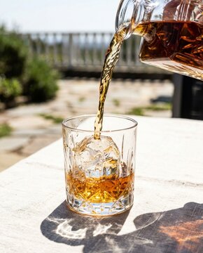 Pouring Amber Whiskey From Decanter Into Glass With Ice Sphere