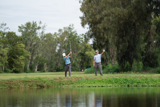 Active aging and golf friendship concept. Happy senior golfer shakes hands with a younger man on a green golf course, celebrating a friendly game. Golf, senior, handshake, friendship, sports.