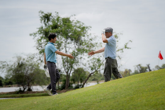 Active aging and golf friendship concept. Happy senior golfer shakes hands with a younger man on a green golf course, celebrating a friendly game. Golf, senior, handshake, friendship, sports.