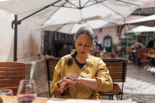 Woman checking the time while waiting at restaurant in Alsace, France