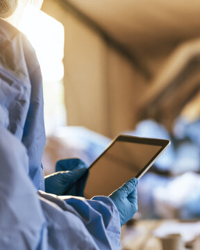 Healthcare worker holding digital tablet in field hospital tent with gloved hands and copy space