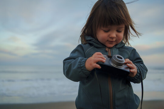 Toddler Examining Camera by the Sea
