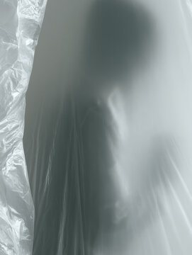 Mobile quarantine tent isolation metaphor extreme close up of clear window showing soft blurred silhouette behind vinyl with quiet clinical tension and large negative space